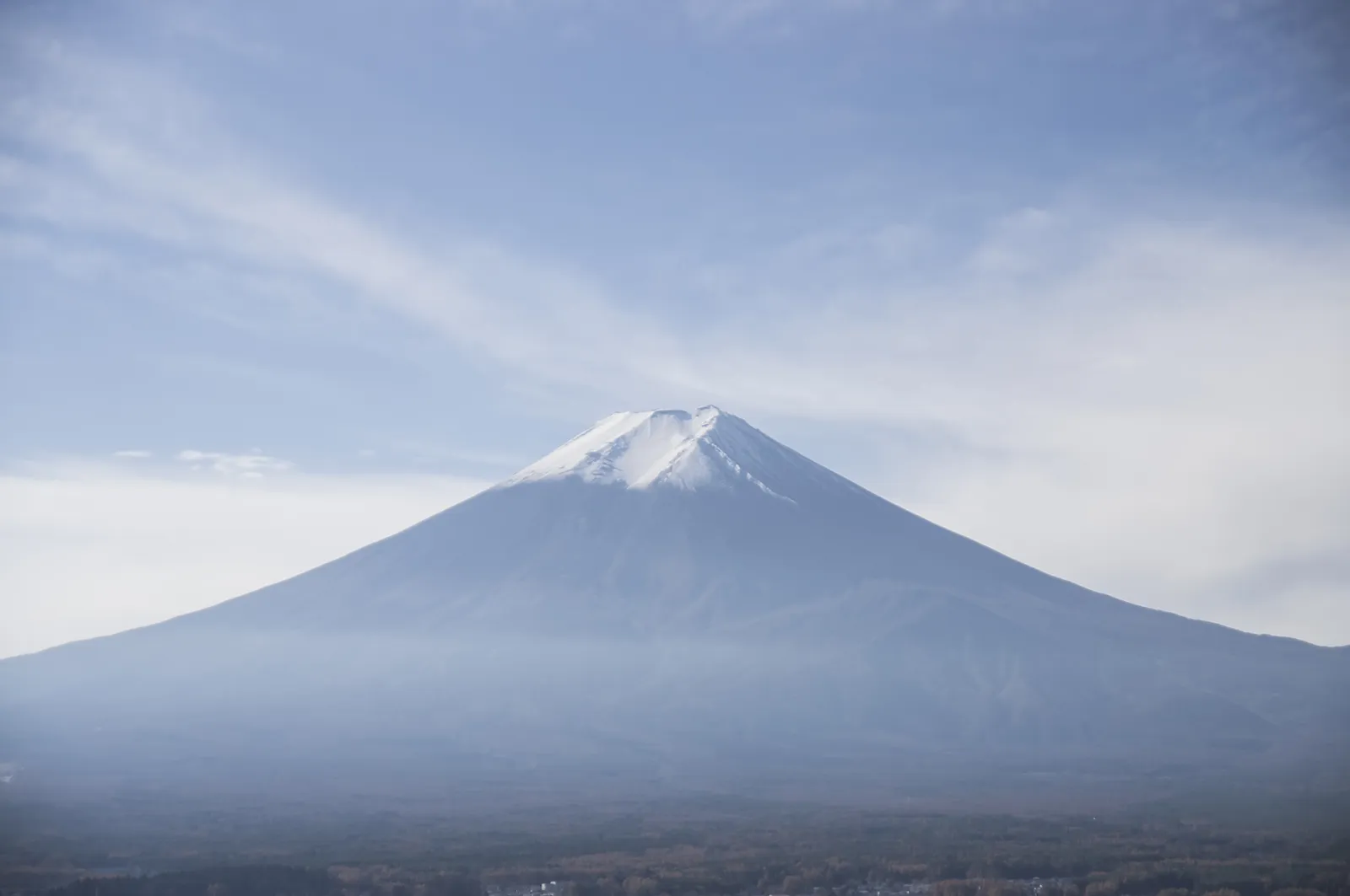 青空と霞を背景にした冠雪の富士山