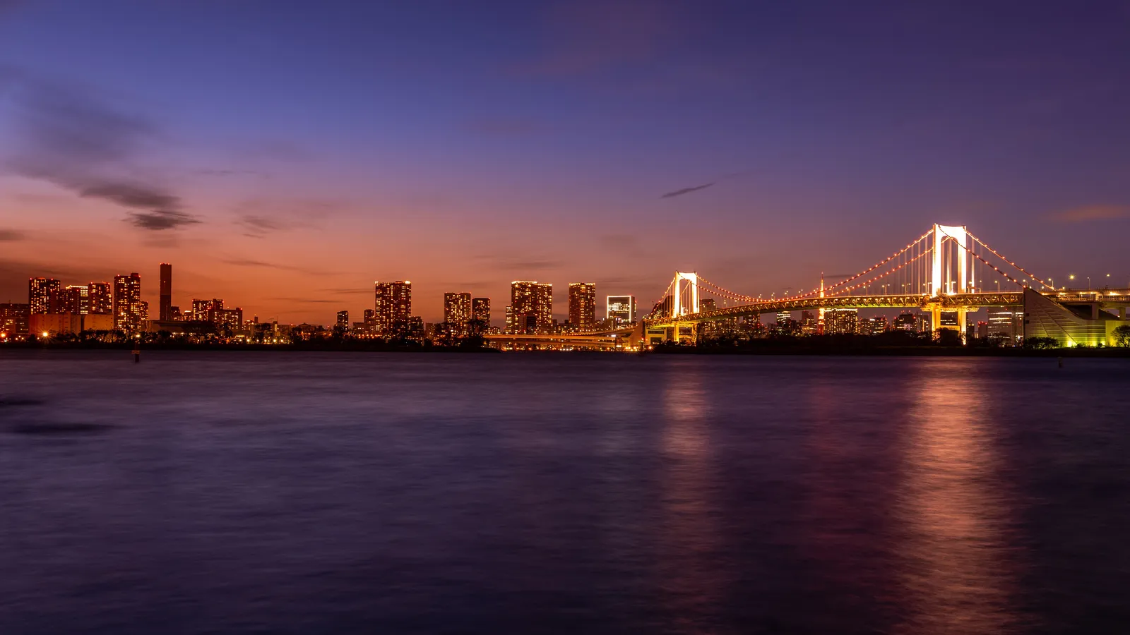 夕暮れの東京湾とライトアップされたレインボーブリッジ